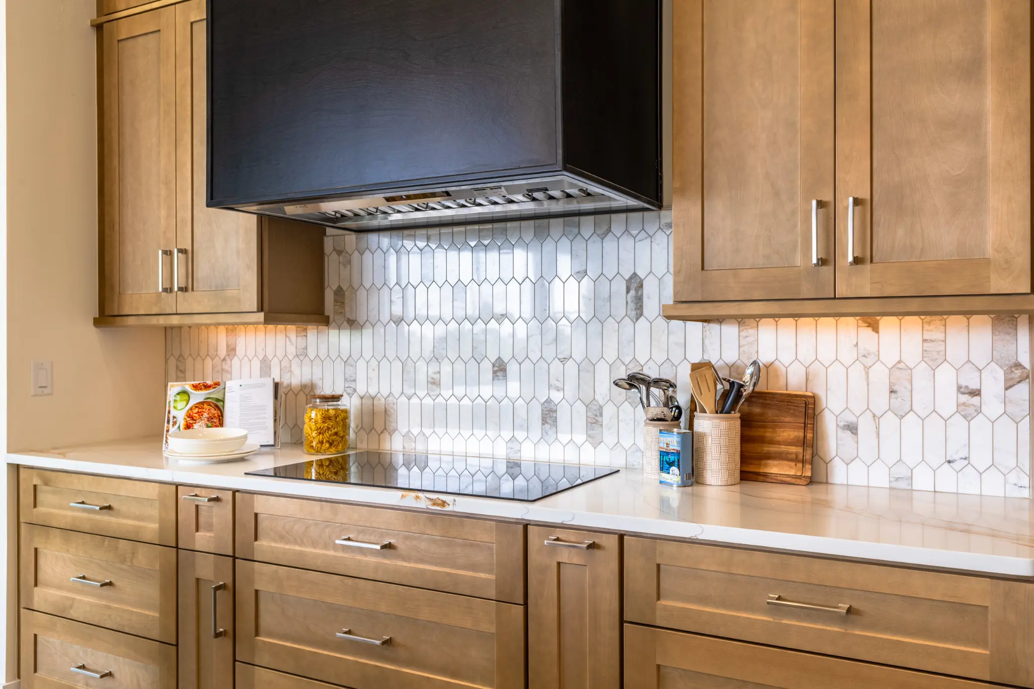 Custom kitchen with marble hexagon backsplash, natural wood cabinetry, quartz countertops, and professional range hood